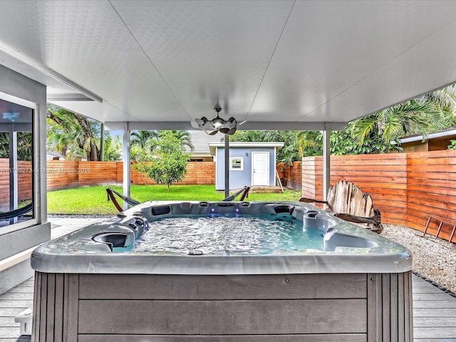 exterior space featuring an outdoor structure, a fenced backyard, a hot tub, and a yard