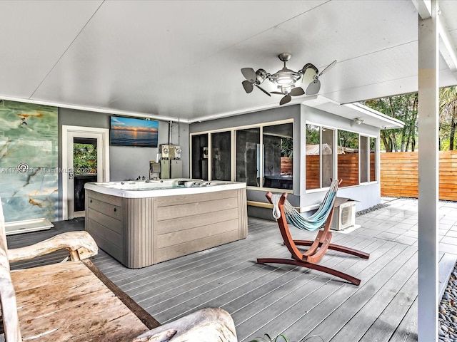 wooden deck featuring a sunroom, a hot tub, and fence