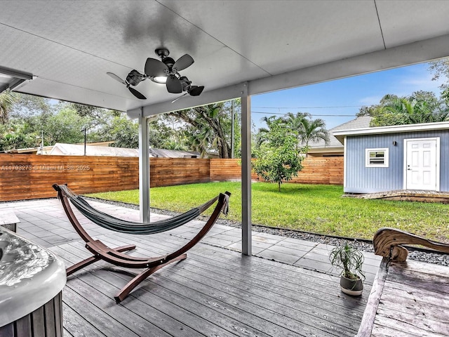 deck featuring an outdoor structure, a fenced backyard, ceiling fan, and a yard