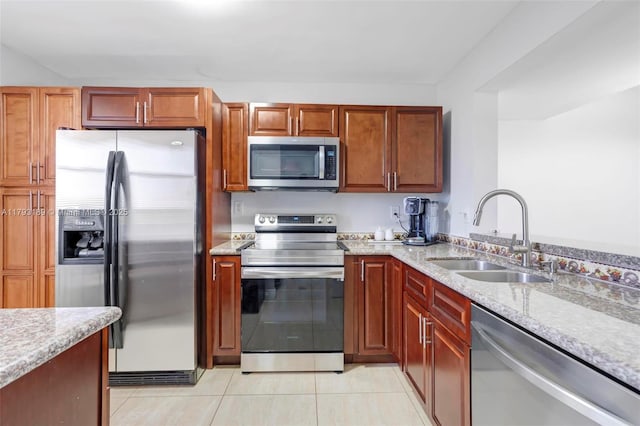 kitchen featuring stainless steel appliances, light stone countertops, light tile patterned floors, and a sink