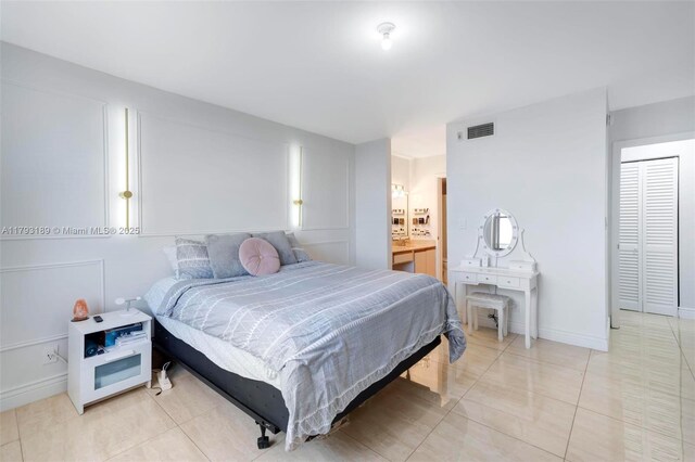 bedroom featuring connected bathroom, visible vents, and light tile patterned floors