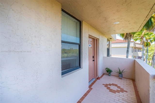 view of exterior entry featuring a balcony and stucco siding
