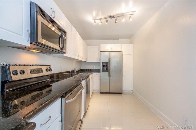 401 69th St Unit 607, Miami Beach, FL 33141 - kitchen featuring baseboards, a sink, white cabinetry, dark stone countertops, and appliances with stainless steel finishes