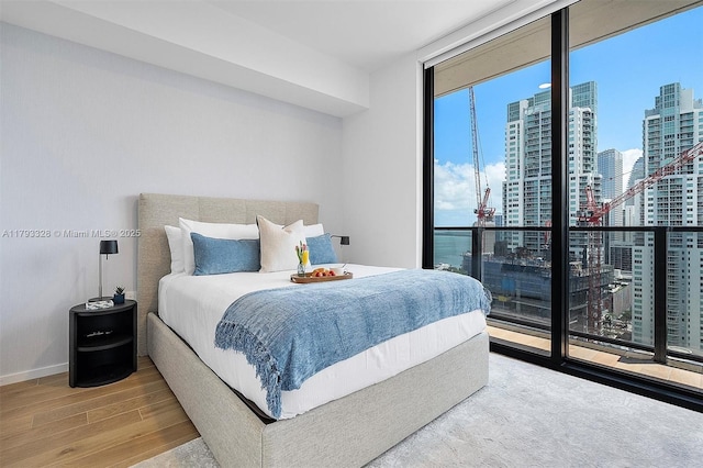 398 NE 5th St Unit 2517, Miami, FL 33132 - bedroom with baseboards, floor to ceiling windows, a city view, and wood finished floors