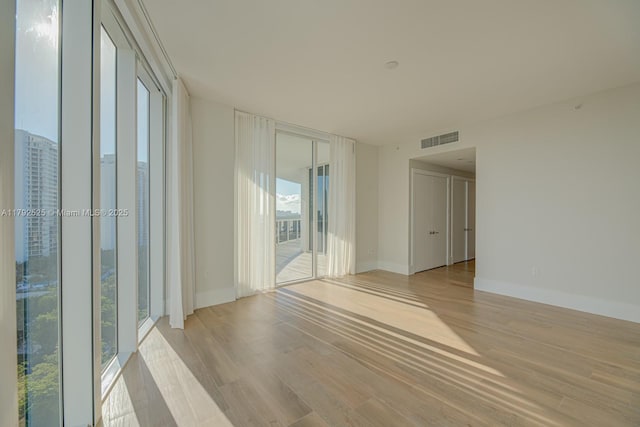 empty room with light wood-style floors, baseboards, and visible vents