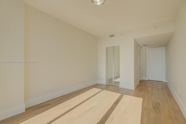 unfurnished bedroom with light wood-style floors, baseboards, visible vents, and a closet