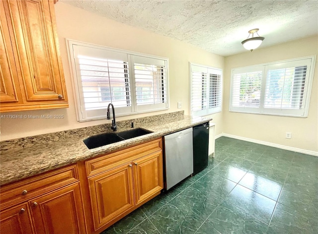 kitchen featuring light stone counters, a sink, dishwasher, a textured ceiling, and brown cabinetry