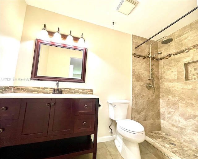 bathroom featuring vanity, visible vents, toilet, tiled shower, and tile patterned floors