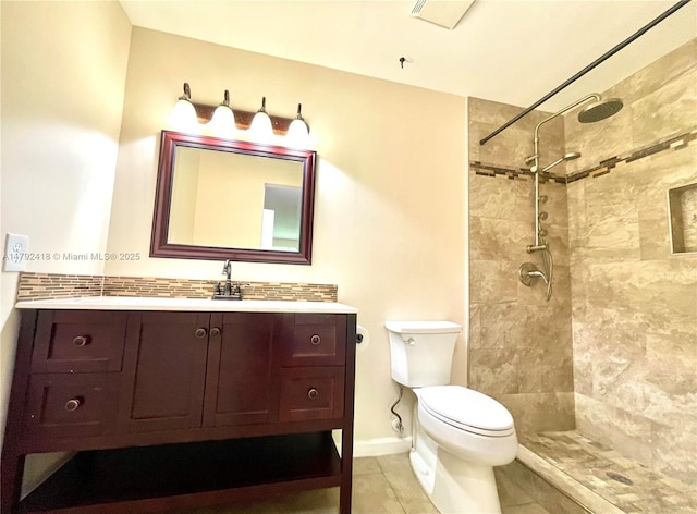 bathroom featuring toilet, tile patterned floors, a tile shower, and vanity