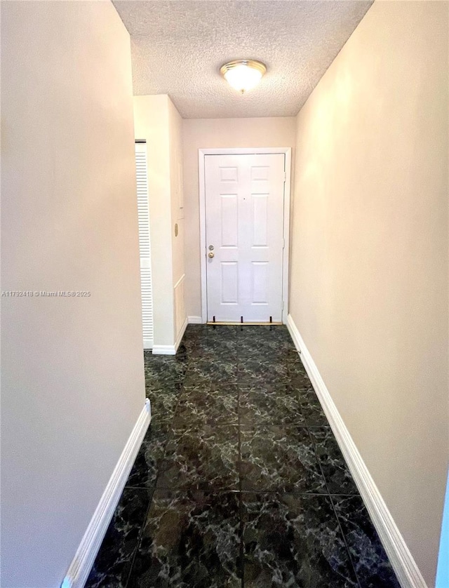 corridor featuring baseboards and a textured ceiling