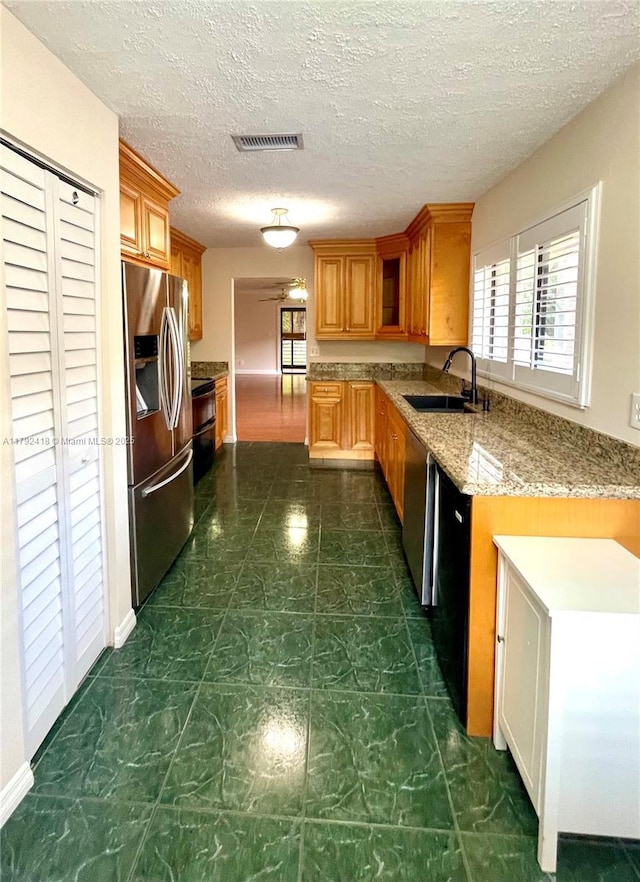 kitchen with stainless steel refrigerator with ice dispenser, a sink, a wealth of natural light, and visible vents