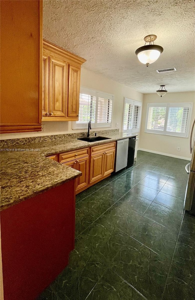 kitchen featuring a textured ceiling, visible vents, a sink, and dishwasher