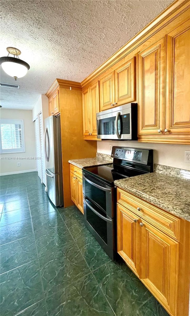kitchen featuring brown cabinets, light stone countertops, stainless steel appliances, baseboards, and visible vents