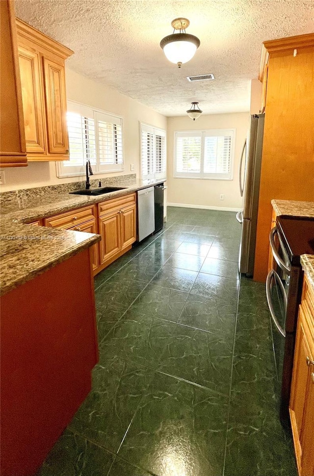 kitchen featuring a textured ceiling, appliances with stainless steel finishes, a sink, and visible vents