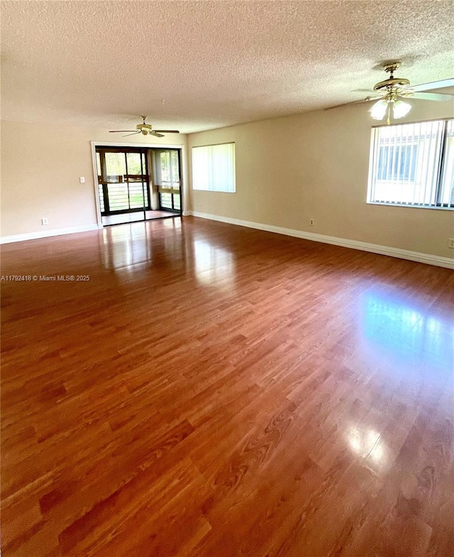 empty room featuring a ceiling fan, a textured ceiling, and wood finished floors