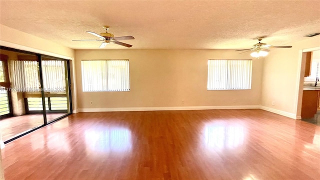 empty room featuring a ceiling fan, a textured ceiling, and wood finished floors
