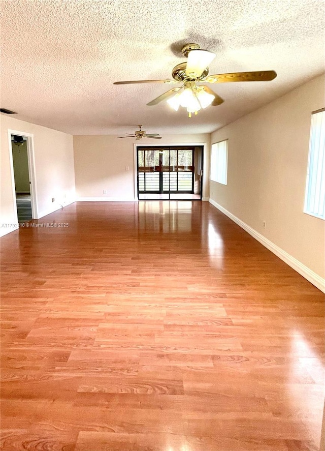 unfurnished room featuring baseboards, a textured ceiling, ceiling fan, and light wood-style flooring