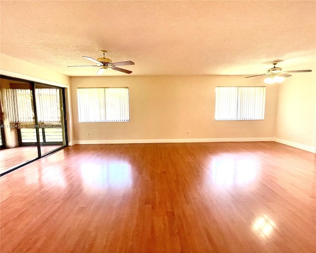 spare room with a ceiling fan, baseboards, wood finished floors, and a textured ceiling