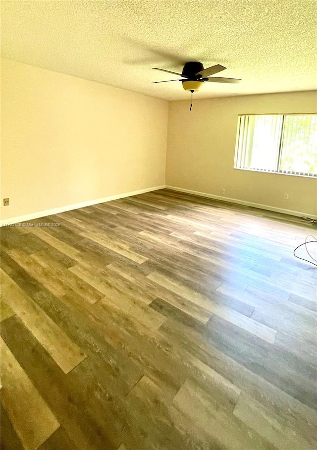 spare room with a textured ceiling, ceiling fan, baseboards, and wood finished floors