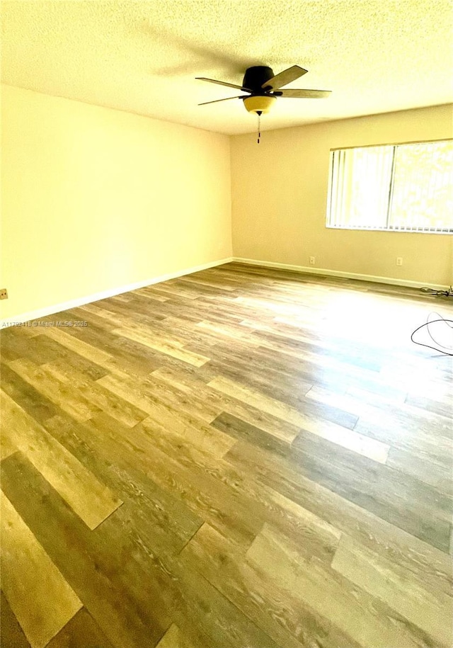 unfurnished room with a textured ceiling, baseboards, a ceiling fan, and wood finished floors