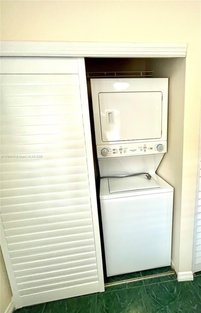 laundry area featuring stacked washer / drying machine, baseboards, and laundry area