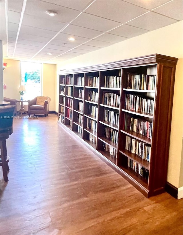 sitting room featuring baseboards, recessed lighting, wood finished floors, and bookshelves