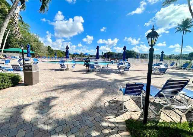 view of community with fence, a pool, and a patio