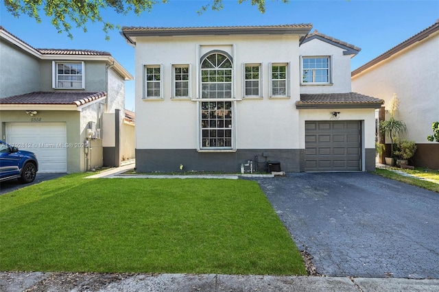 mediterranean / spanish home with a tiled roof, driveway, a front yard, and stucco siding