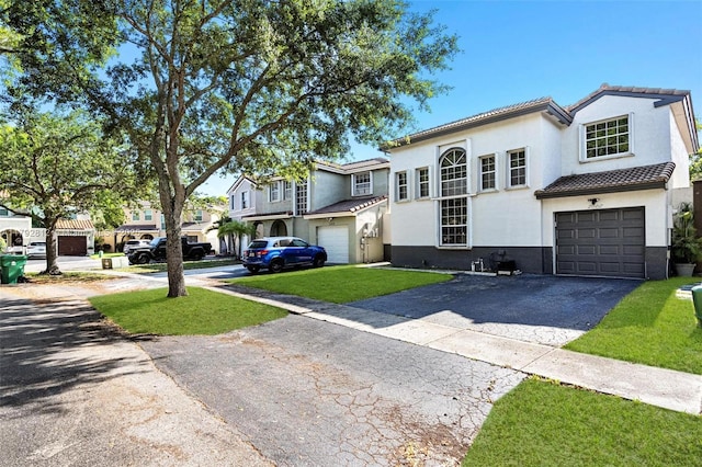 view of front of house with an attached garage, aphalt driveway, stucco siding, a front yard, and a tiled roof