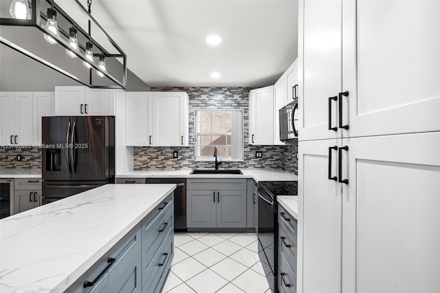 kitchen with a sink, gray cabinetry, black appliances, and tasteful backsplash