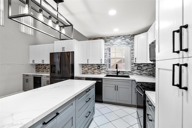 kitchen featuring a sink, beverage cooler, backsplash, gray cabinetry, and black appliances