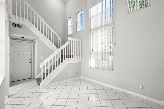 stairs featuring baseboards, a high ceiling, and visible vents
