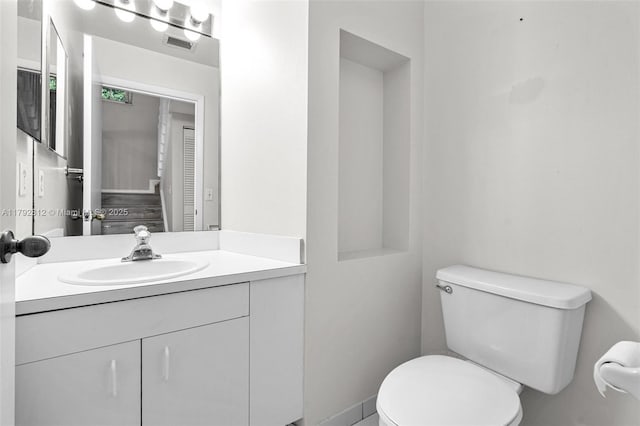 bathroom featuring vanity, toilet, and visible vents