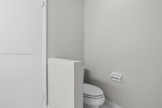 bathroom featuring baseboards, tile patterned floors, and toilet
