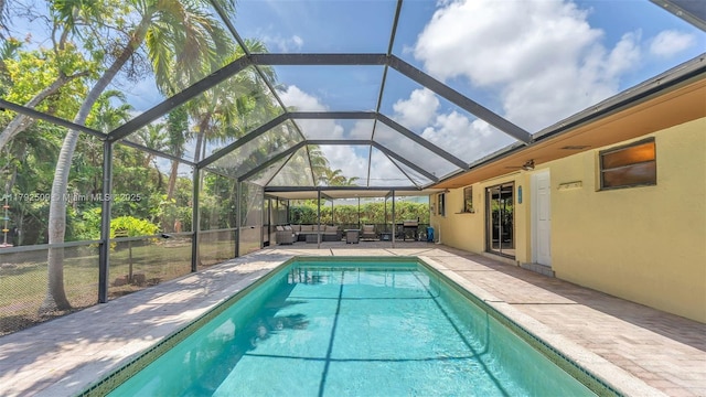 outdoor pool with an outdoor living space, glass enclosure, and a patio