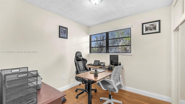 office featuring baseboards, light wood finished floors, and a textured ceiling