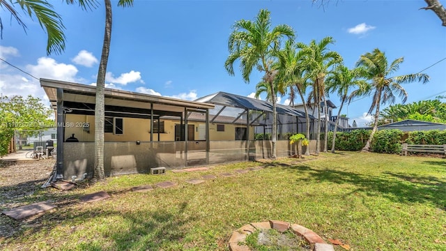 rear view of property with a lawn, a lanai, stucco siding, and fence