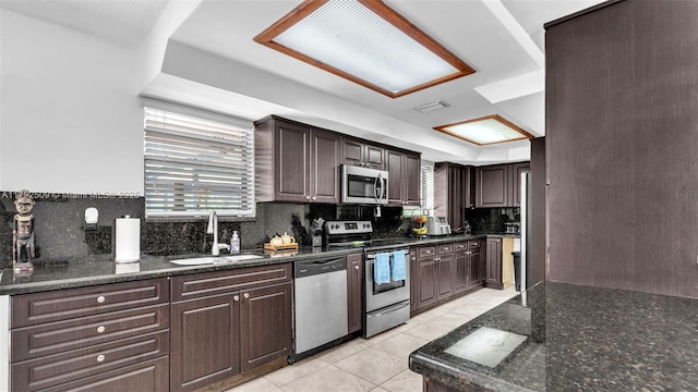 kitchen featuring dark brown cabinets, a sink, stainless steel appliances, light tile patterned floors, and backsplash
