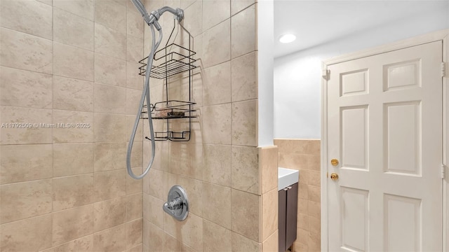 bathroom with recessed lighting, tile walls, wainscoting, and tiled shower