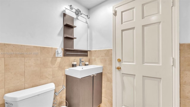 bathroom featuring toilet, tile walls, wainscoting, and vanity