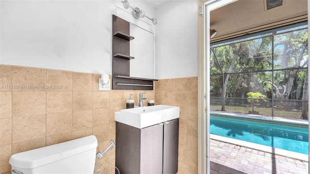 half bath featuring toilet, tile walls, wainscoting, and vanity