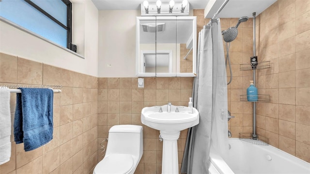 bathroom with tile walls, toilet, and shower / tub combo
