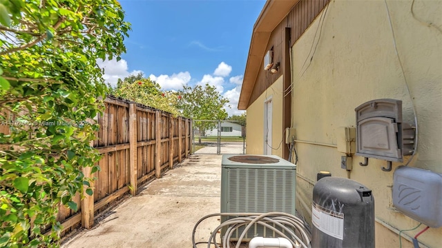view of home's exterior featuring stucco siding, a gate, central AC, and fence
