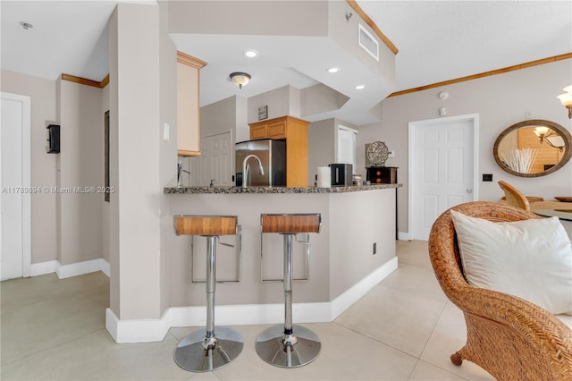 kitchen with dark stone counters, baseboards, stainless steel refrigerator with ice dispenser, and visible vents