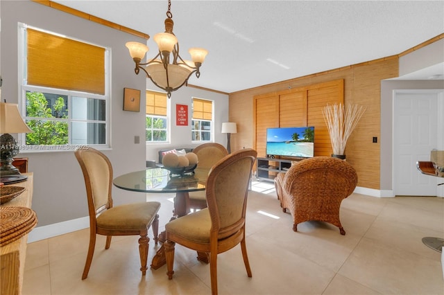 dining space featuring crown molding, baseboards, an inviting chandelier, and light tile patterned floors