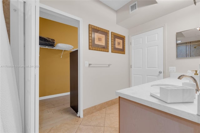 bathroom featuring visible vents, vanity, baseboards, tile patterned floors, and a spacious closet