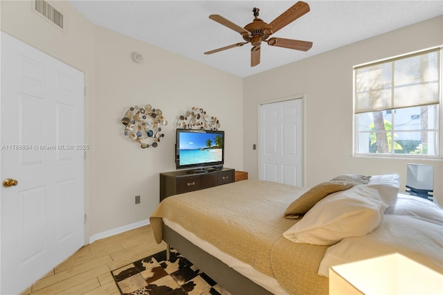 bedroom featuring light wood-style floors, baseboards, ceiling fan, and visible vents