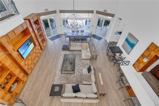living area featuring an inviting chandelier, a towering ceiling, and wood finished floors