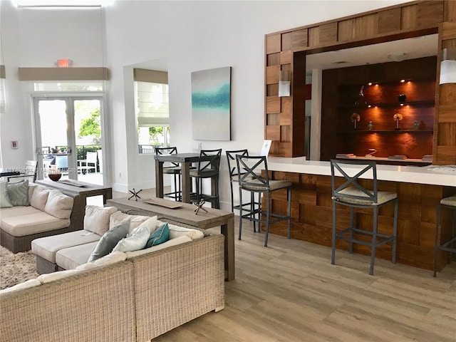 living area with french doors, bar, a towering ceiling, and wood finished floors