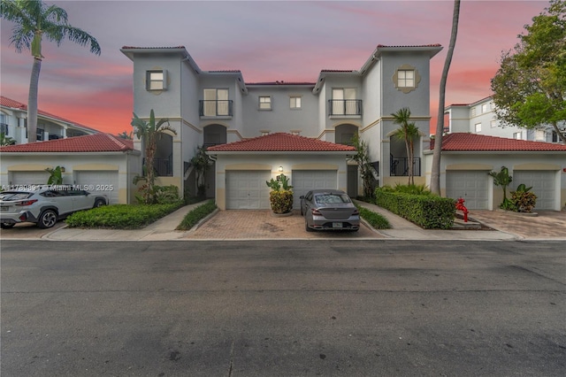 view of front of house with a tiled roof, stucco siding, decorative driveway, and a garage